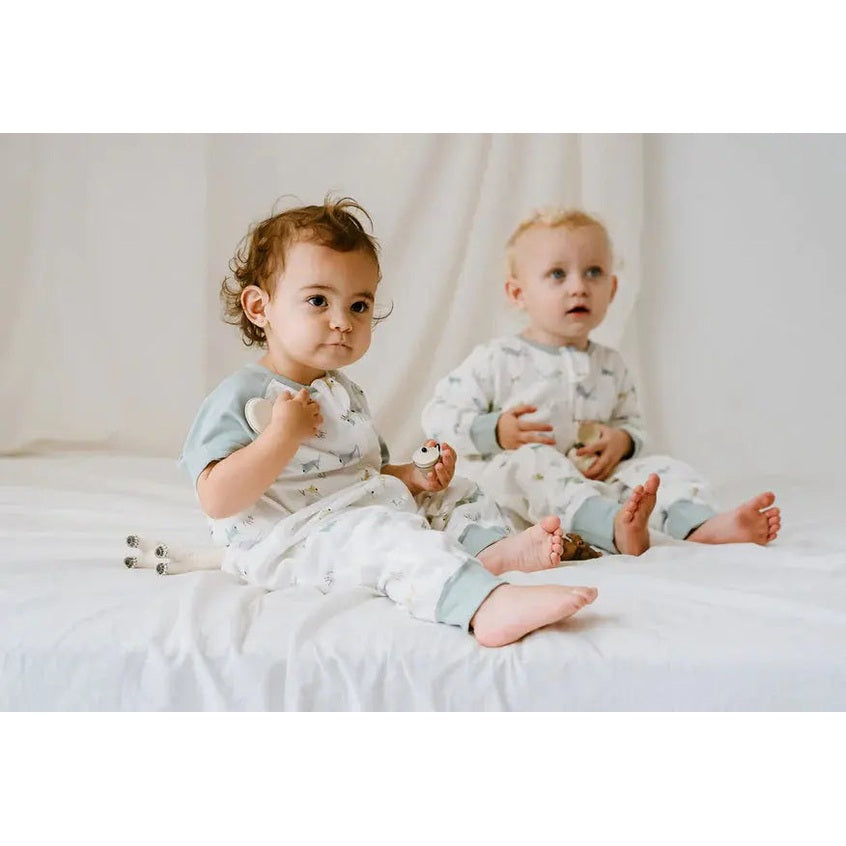 Nest Designs Raglan Bamboo Pima Short Sleeve Sleep Suit 0.6 Tog for babies, two toddlers sit cozily in pale gray sleepwear.