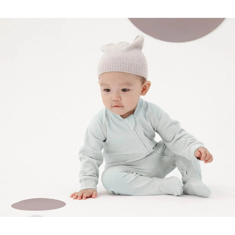 Nest Designs Tanboocel Long Sleeve Footed Sleeper Pantone Ice Flow; baby crawls in pale blue sleepwear on a white background.