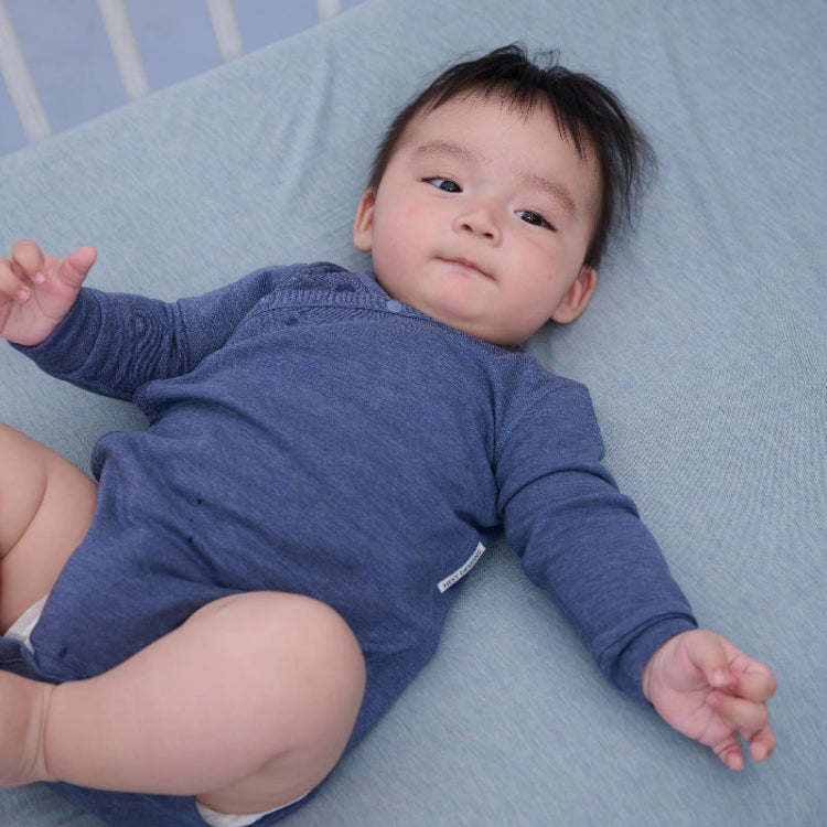 Nest Designs Tanboocel long-sleeve kimono onesie in Vintage Indigo for baby on blue blanket