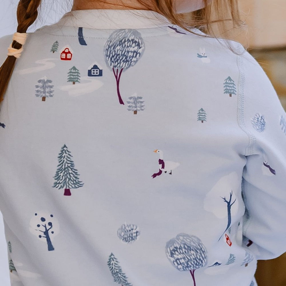 Nest Designs two-piece long-sleeve pajama set in pale blue with snowy trees pattern