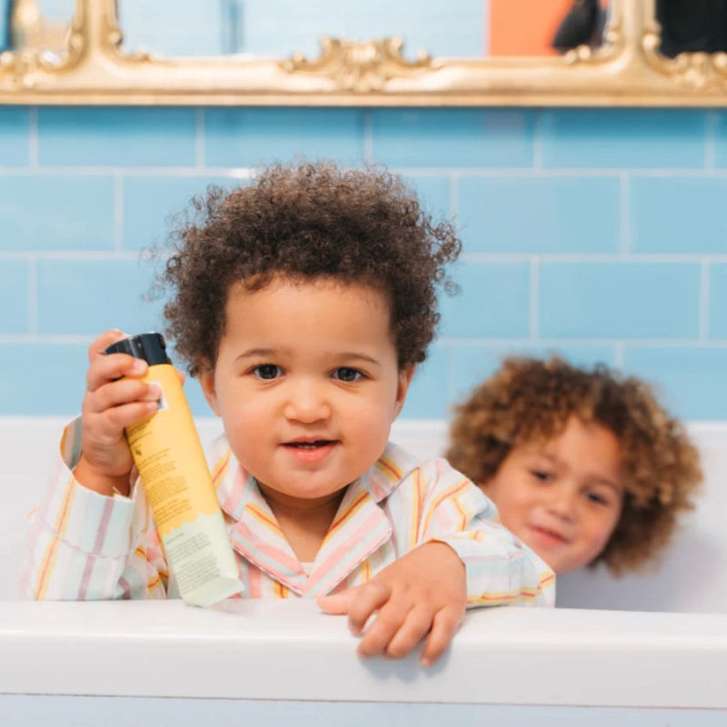 No Nasties Kids Natural Hair Paste 125 ml bottle in yellow with coconut-lime scent, held by a toddler