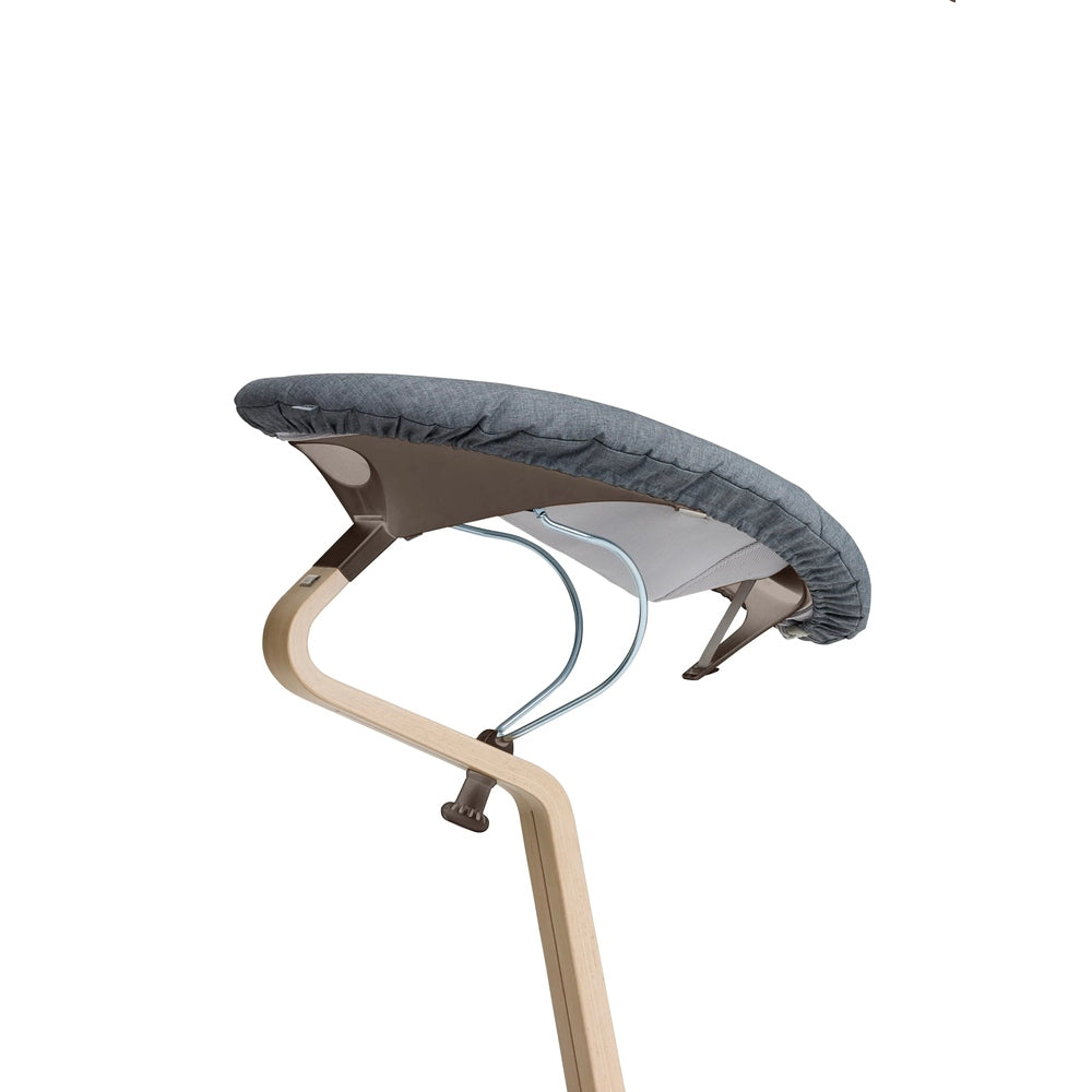 NOMI Baby high chair cushion in dark gray fabric secured to a curved light-wood frame.