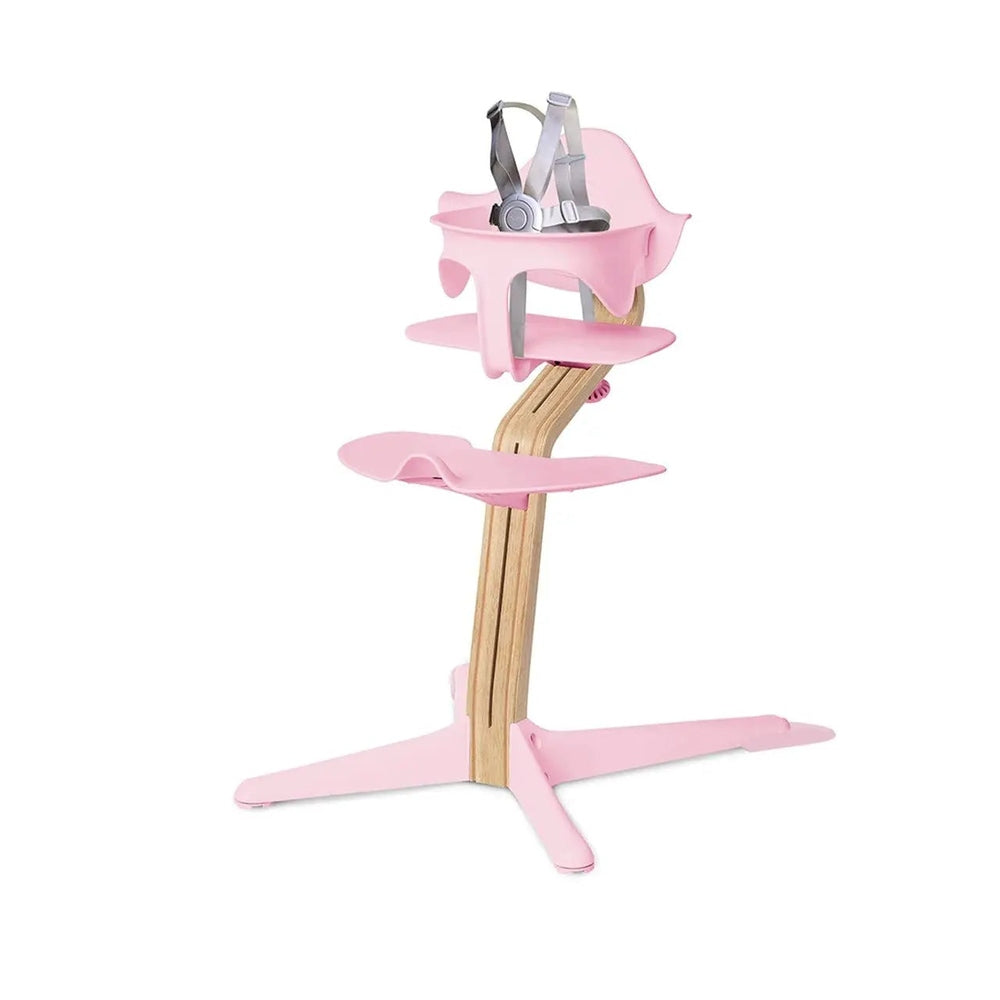 NOMI Highchair White Oak with pink cushions and trays, straps fastened for safe mealtime.