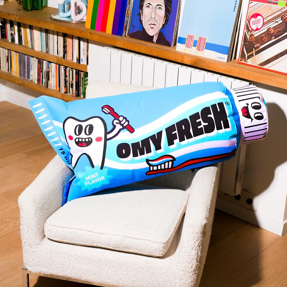 OMY Fresh Giant inflatable pillow in bright blue draped over a chair, tooth graphic and mint flavor label visible.