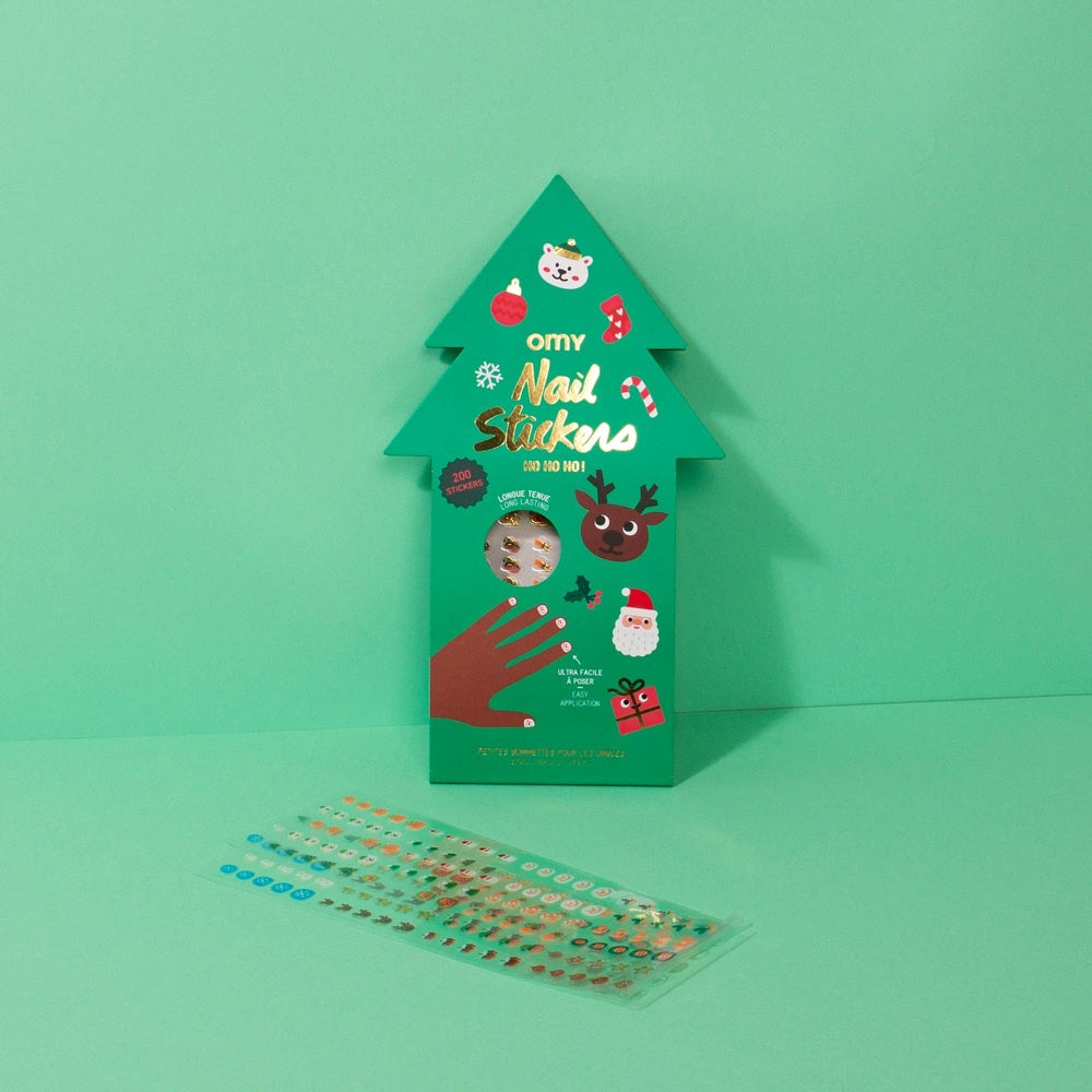 OMY Ho Ho Ho Holiday Nail Stickers kit in a green tree box with a colorful sticker sheet spread for quick nail art.
