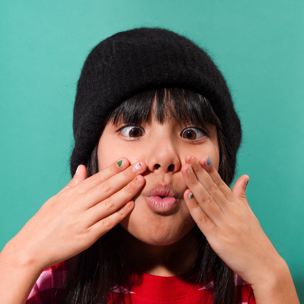 OMY Ho Ho Ho Holiday nail stickers; a girl smiles as she applies tiny festive decals to her nails.
