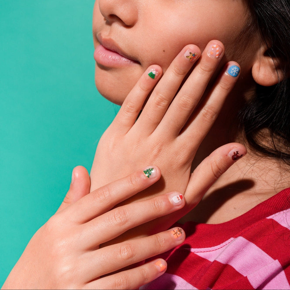 OMY Ho Ho Ho Holiday nail stickers on fingertips, revealing festive Christmas tree, snowflake, and candy cane designs.