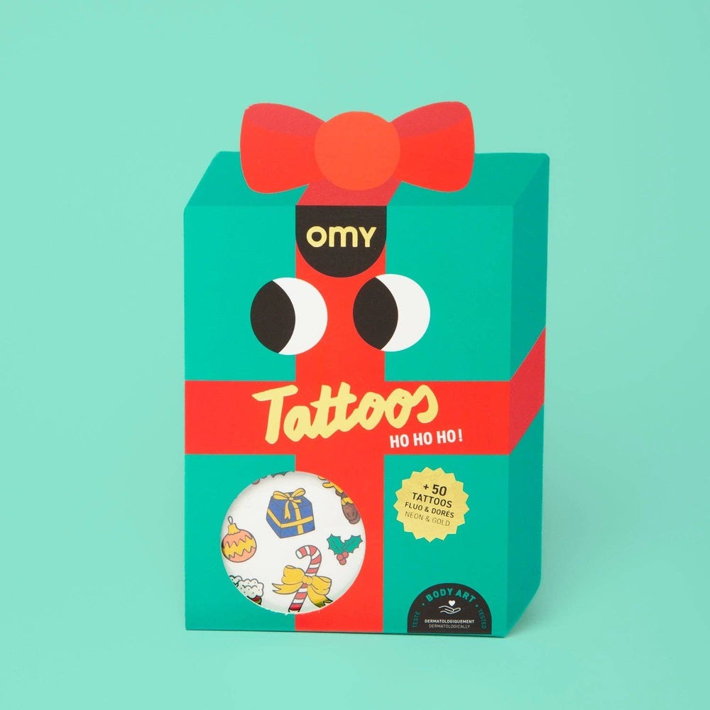 OMY Ho Ho Ho Holiday! temporary tattoos on turquoise gift box with red bow, featuring +50 festive designs.