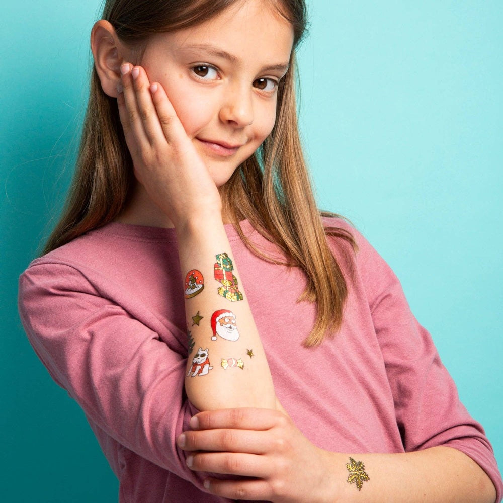 OMY Hohoho Holiday! temporary tattoos on a girl’s forearm and wrist featuring festive designs.