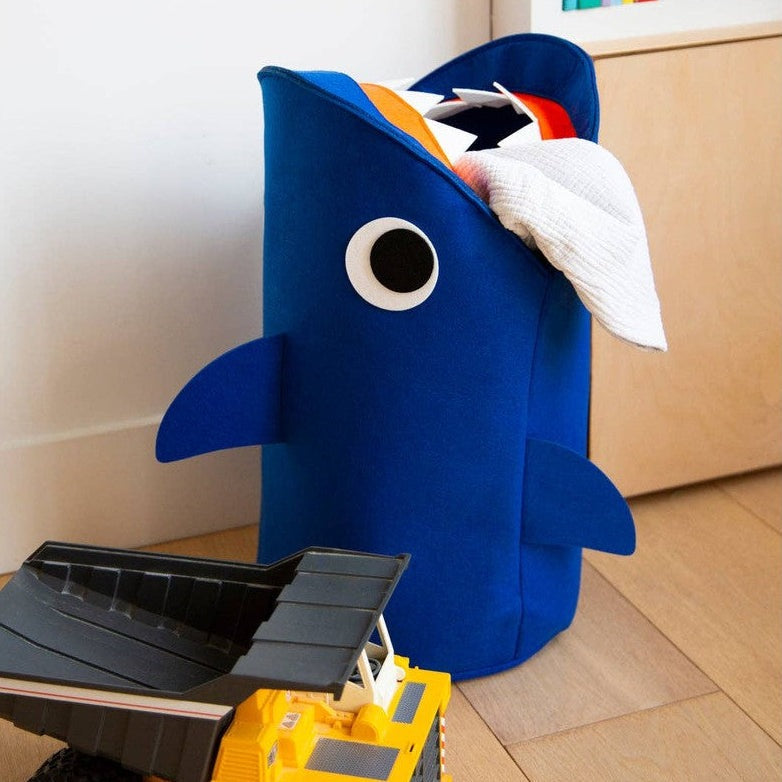 OMY Tidy Bag Sharky, blue shark-shaped storage bag with fins, storing a towel and toy truck.