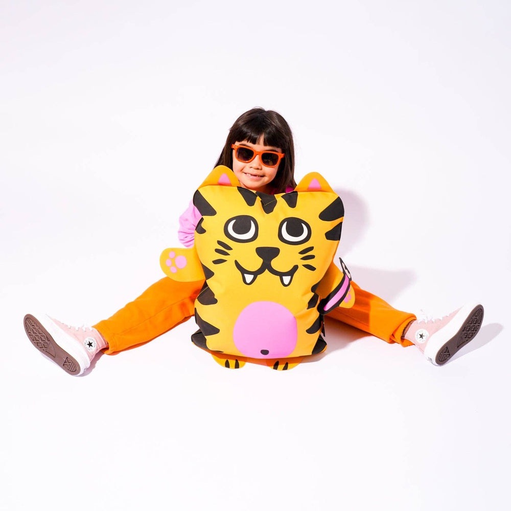 OMY Tiga Super inflatable pillow: yellow tiger design with pink nose, carried by a smiling child in orange outfit.