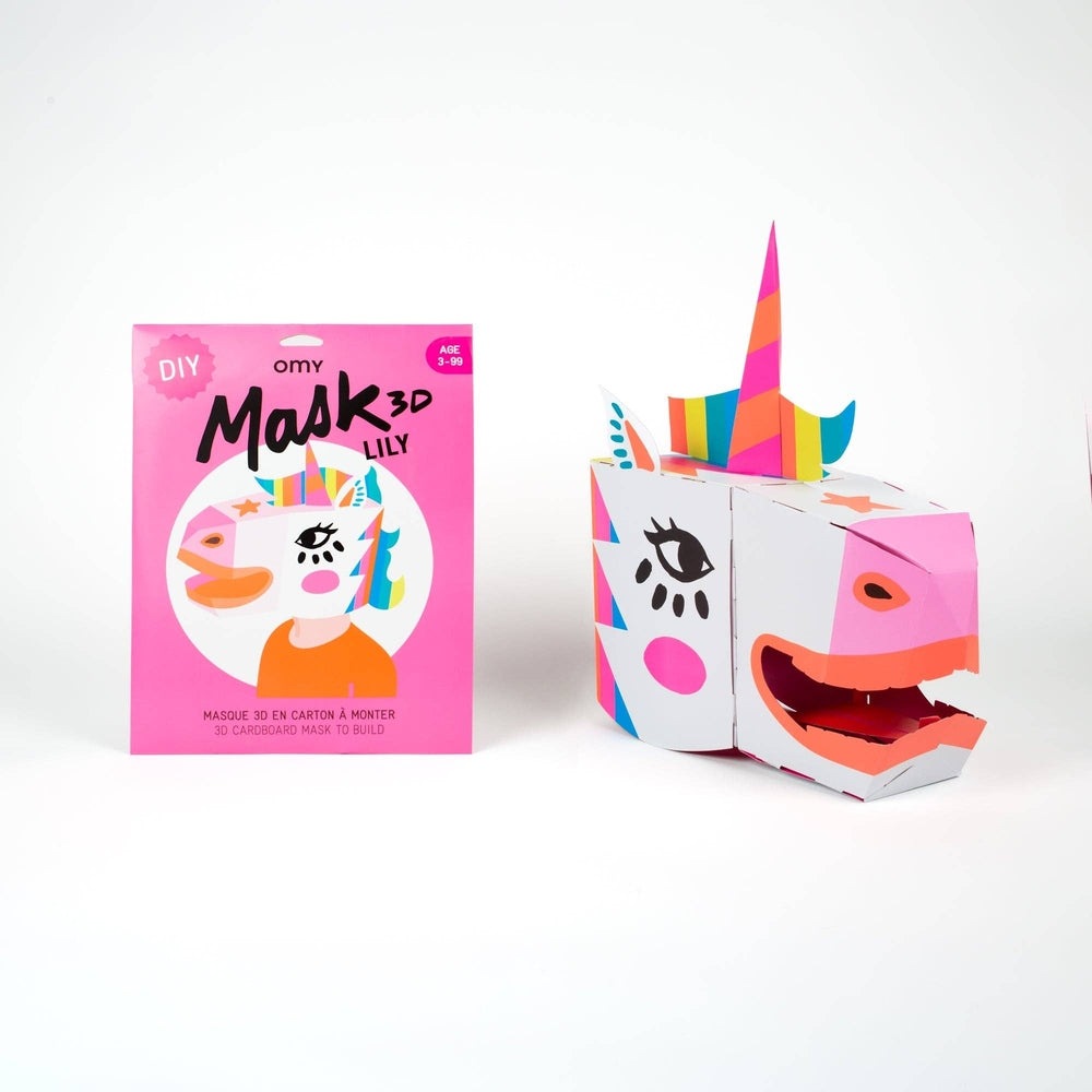 OMY Unicorn 3D mask kit, pink packaging beside a colorful, assembled unicorn cardboard mask on display.