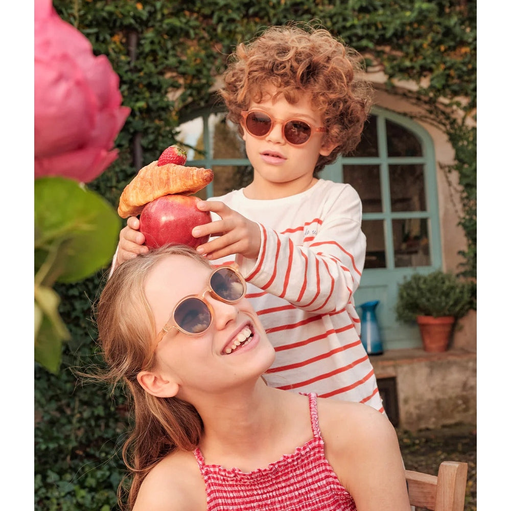 Two children playing with a toy in a garden setting