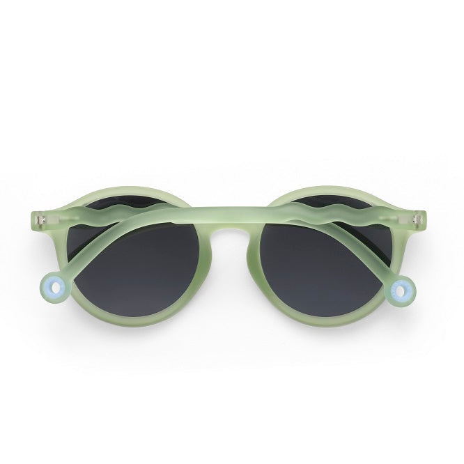 Olivio & Co Oval Sunglasses Junior+ in light leaf green with dark lenses, laid flat.
