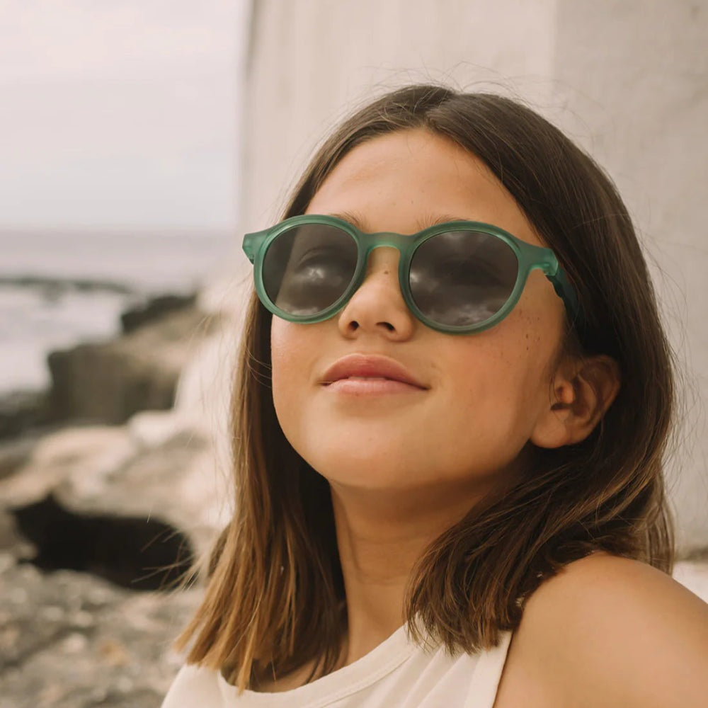 Olivio & Co oval kids sunglasses in olive green worn by girl outdoors