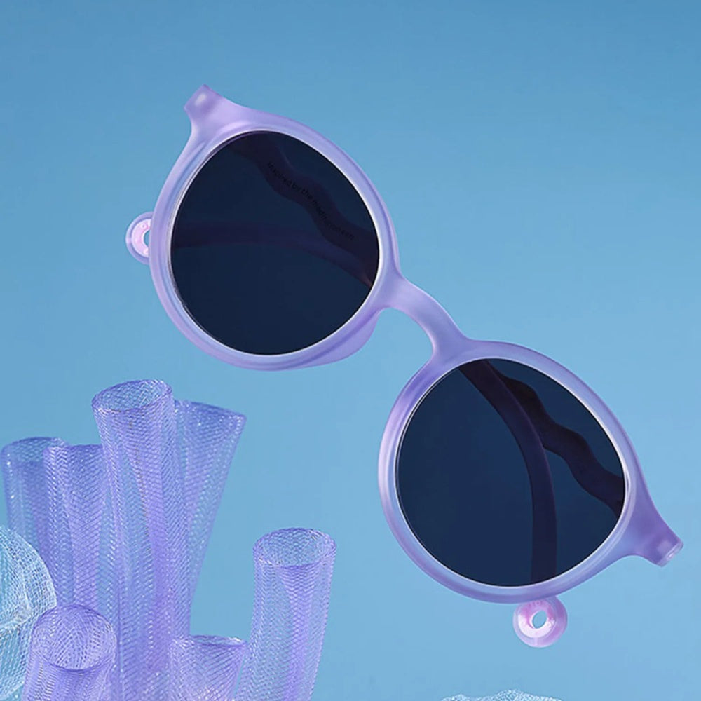 Olivio & Co Oval Sunglasses for Kids, Coral Reef Purple Coral frames with dark lenses, suspended above purple coral.