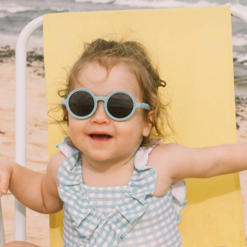 Olivio & Co round reef-blue baby sunglasses on a sunny beach chair
