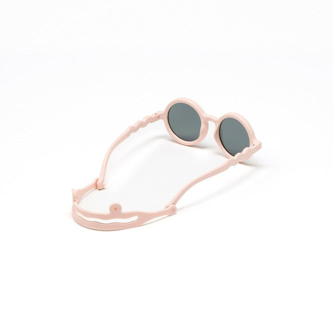 OLIVIO & CO Round Sunglasses Kids Classic Olivio Shell Pink with adjustable pink strap, laid out to display round gray lenses.