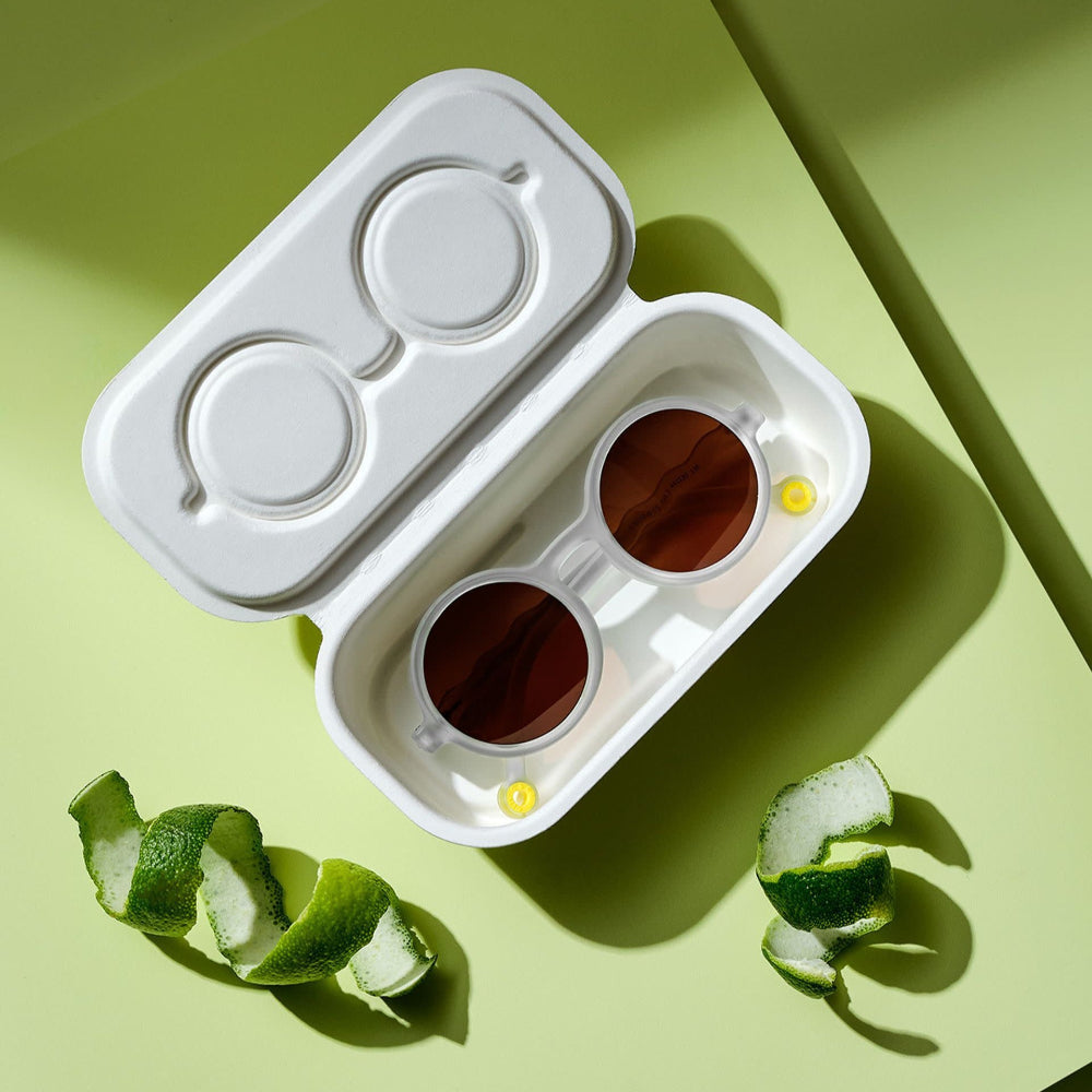 Olivio & Co Round Sunglasses Kids Citrus Garden in a white case; two brown-lens glasses shown on a lime backdrop