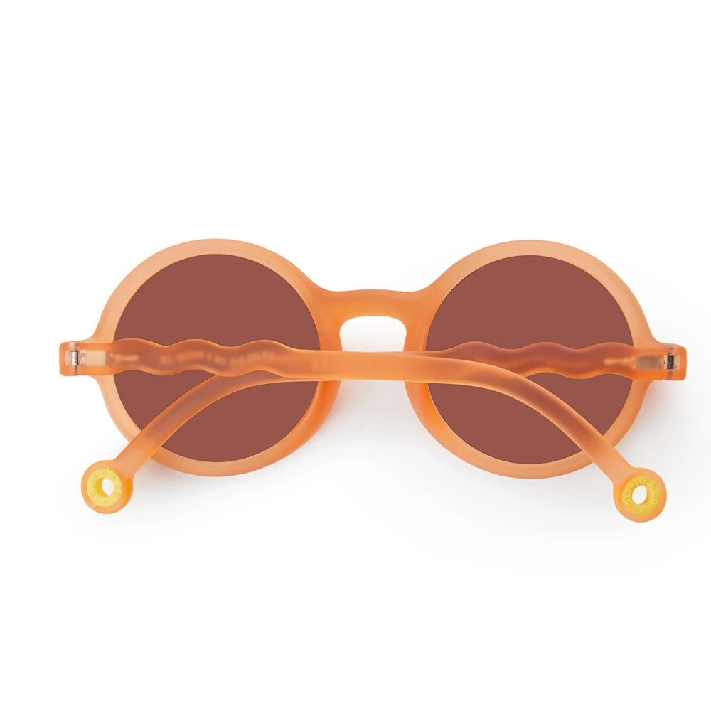 OLIVIO & CO Round Sunglasses Kids Citrus Garden Grapefruit Pink with orange frames and brown lenses, temples crossed over front.