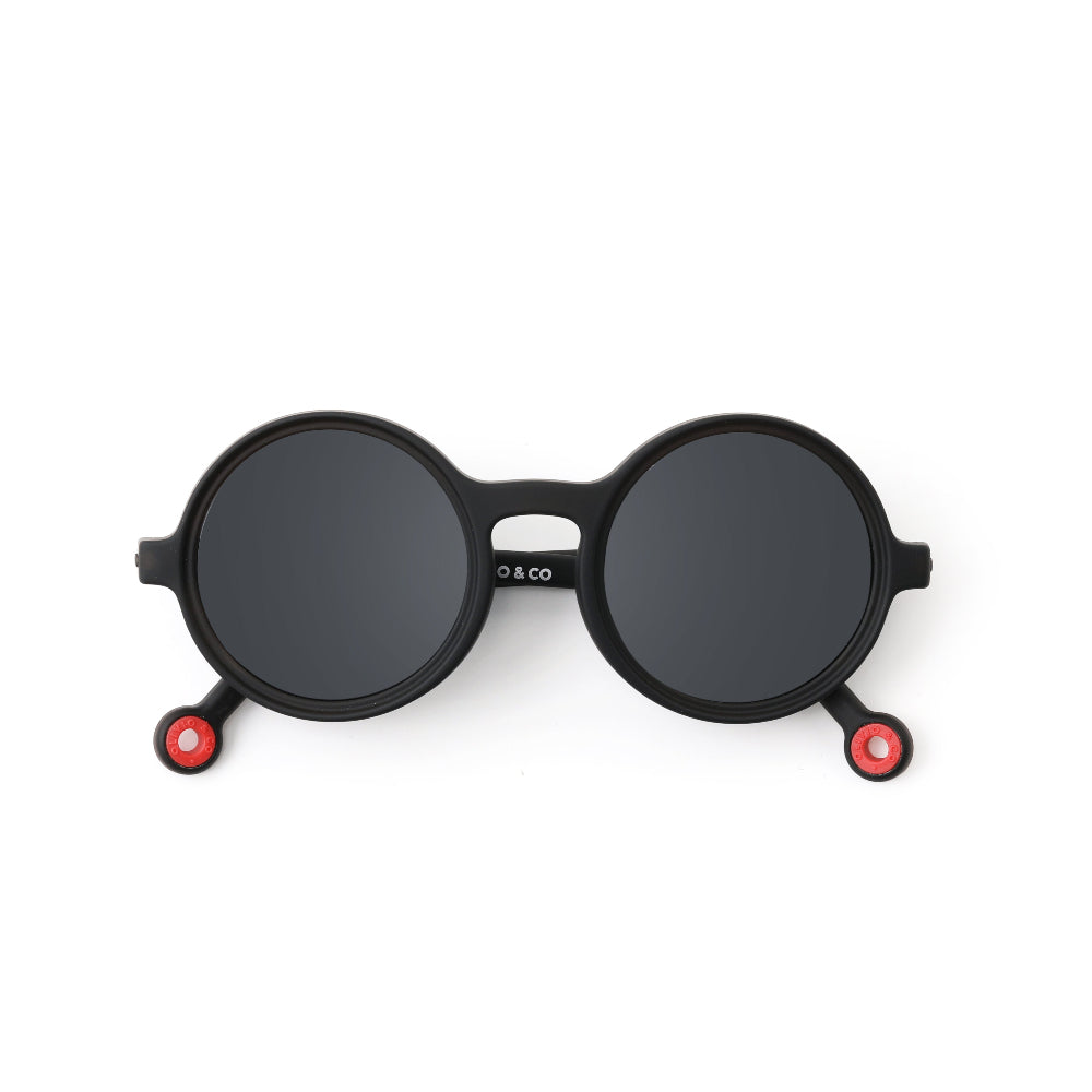 OLIVIO & CO Round Sunglasses for Kids in black frames with dark lenses and red-tipped arms laid flat.