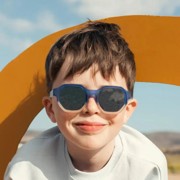 Olivio & Co Square Sunglasses Junior+ Creative Edition D Deep Sea on a smiling boy with blue frames and dark lenses.