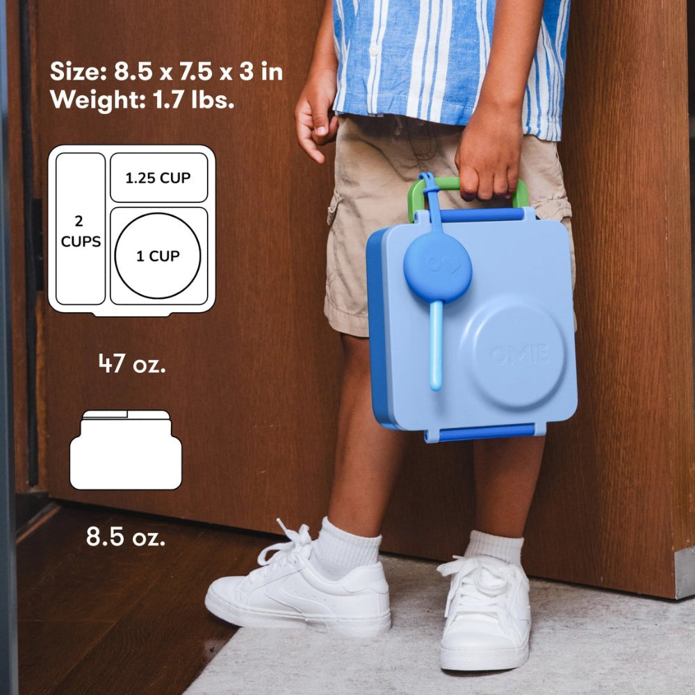 Omiebox Version 2 blue lunch container with green handle carried by a child, highlighting its compact, portable design.