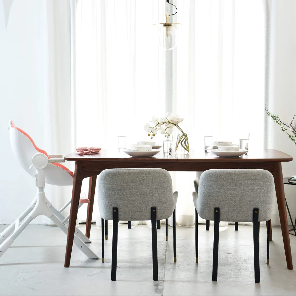 Oribel Cocoon Z High Chair Lounger; white with coral pink accents around a wooden dining table with gray chairs
