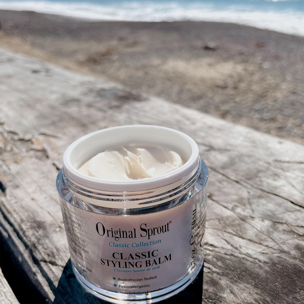 Original Sprout Classic Styling Balm in White, open jar on weathered wood by the beach.