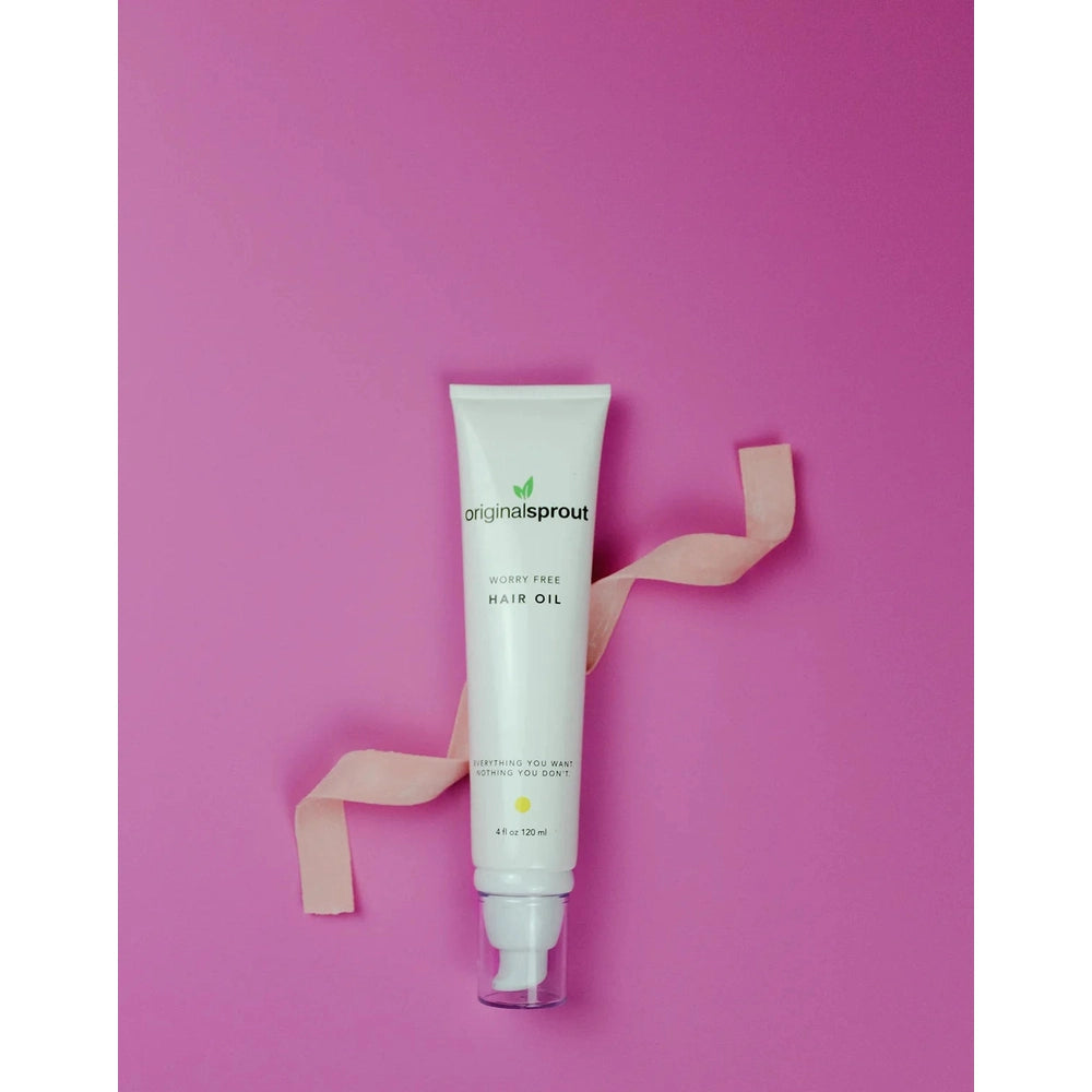 Original Sprout Worry Free Hair Oil tube, white with green logo, 4 oz, against pink background