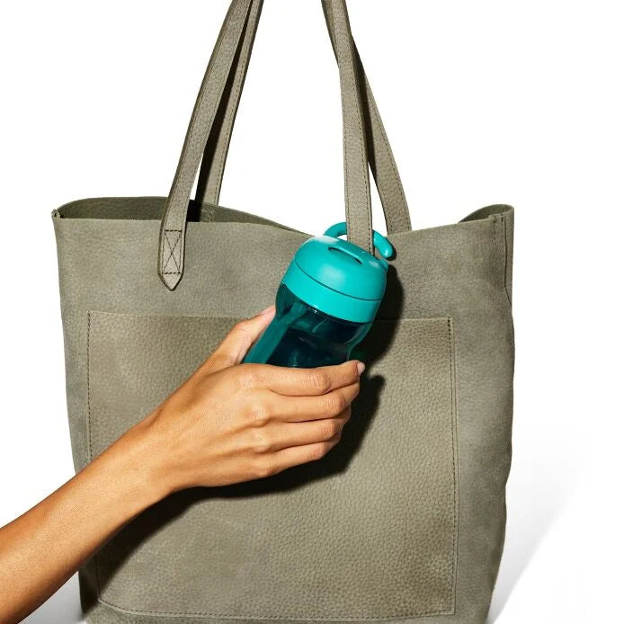 OXO Tot Adventure water bottle 12 oz in teal held beside a gray tote bag