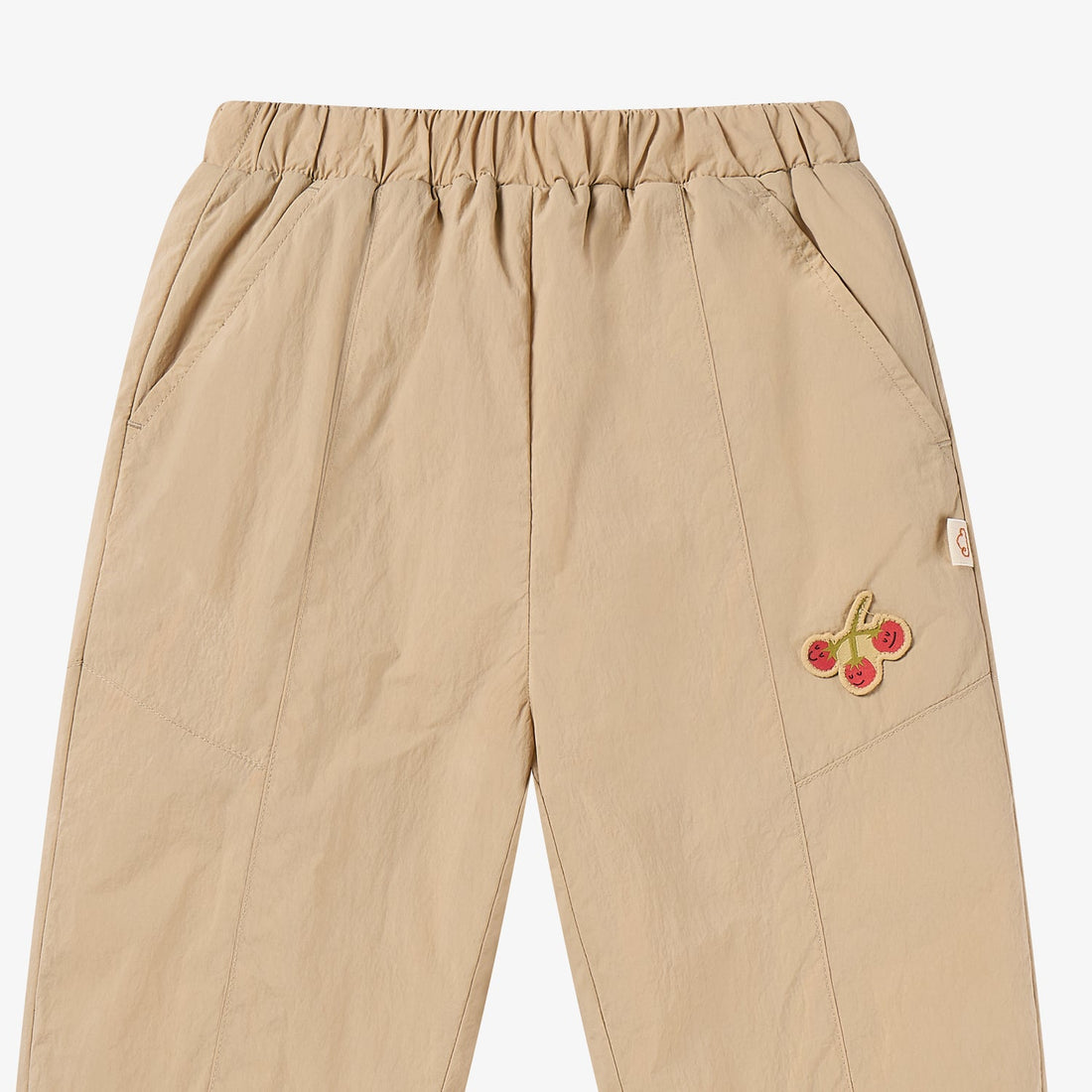 Nest Designs Biscuits & Vine Pants in Toast beige, upper-front detail with elastic waist, panel seams, and cherry embroidery