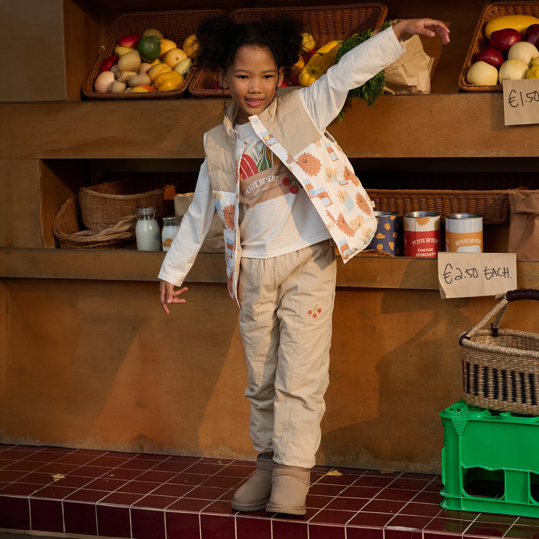 Nest Designs Biscuits & Vine Pants in Toast beige, worn by a child balancing with one arm raised at a market stall