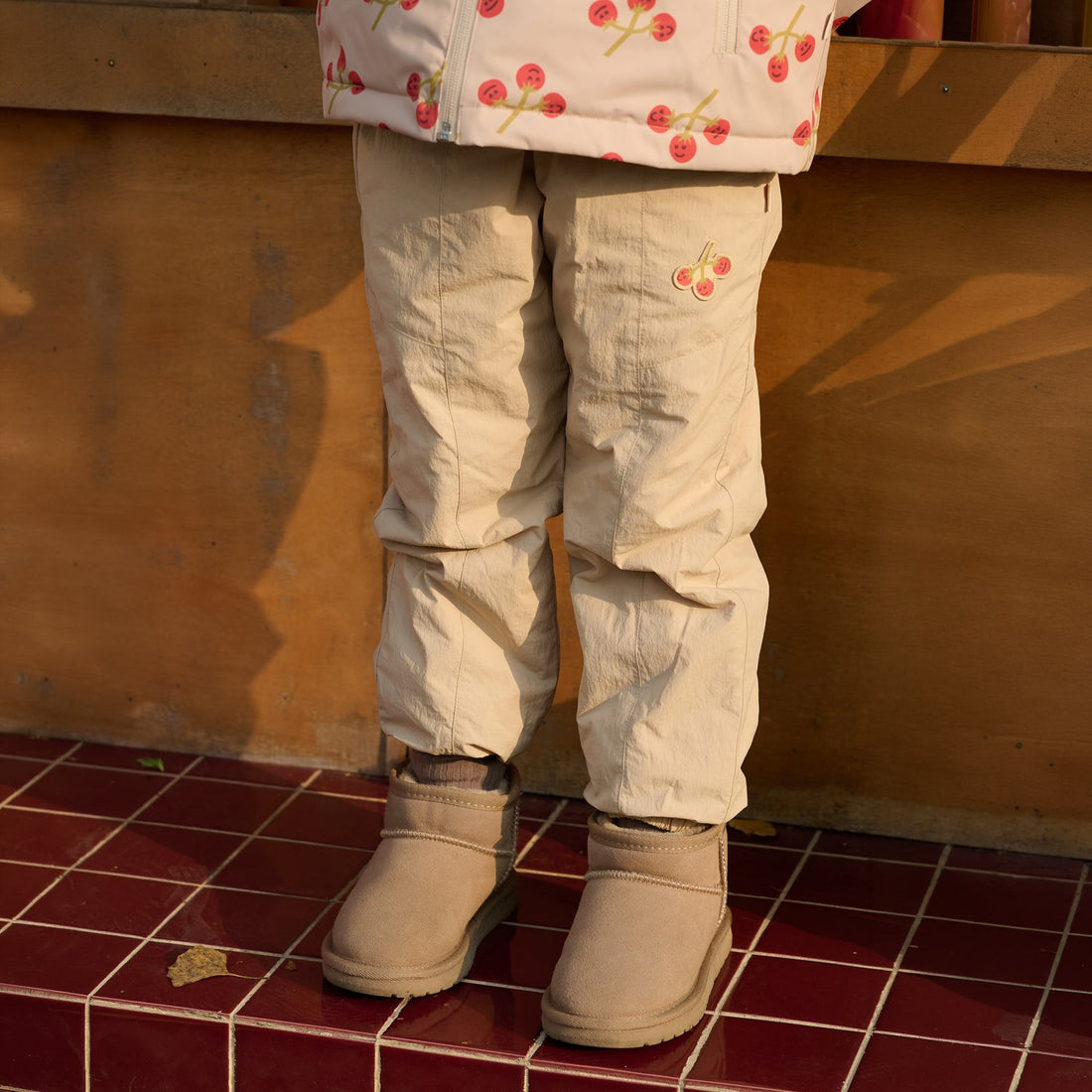 Nest Designs Biscuits & Vine Pants in Toast beige, worn close-up of paneled legs, gathered ankles, and tan boots