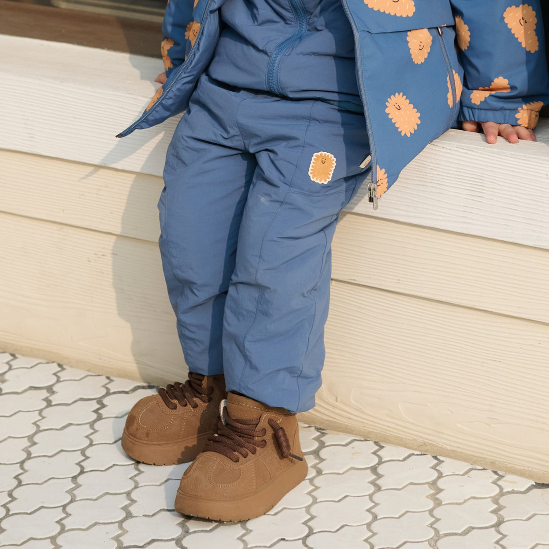 Nest Designs Biscuits & Vine Pants in Sea Blue, seated close-up with gathered legs and brown lace-up boots