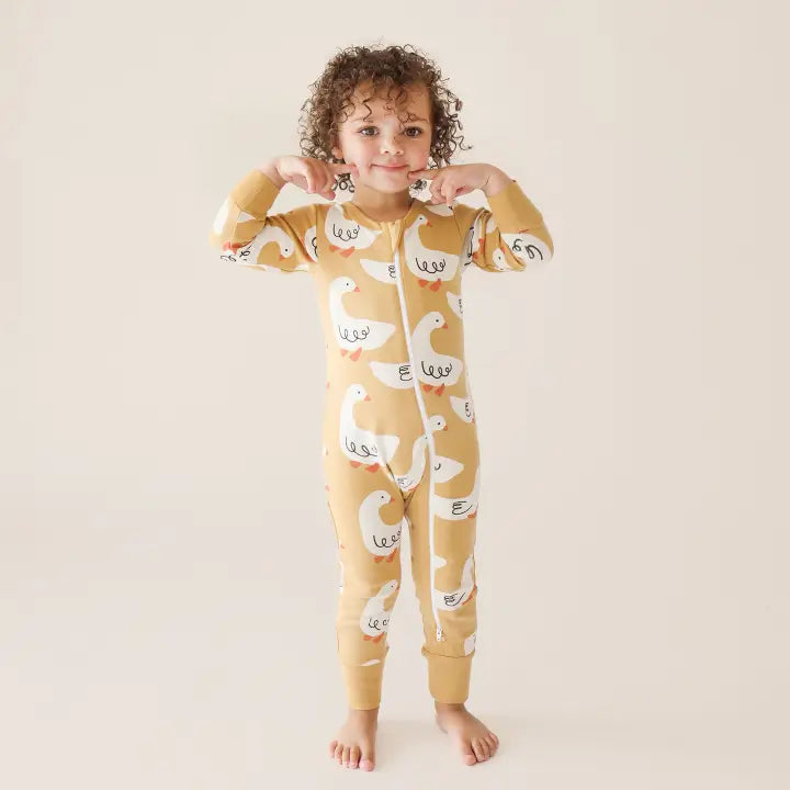 PARADE Parade Organic Signature 2-Way Zip Romper in mustard duck print; toddler stands barefoot, gripping the zipper.