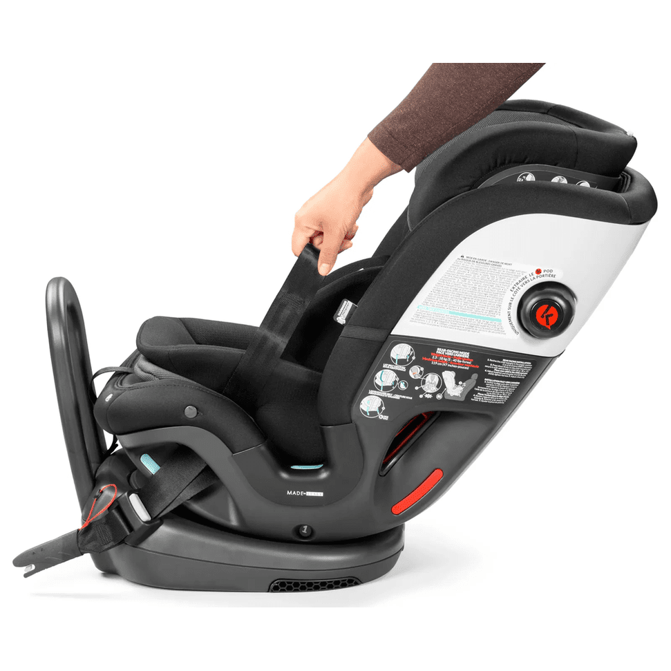 Peg Perego Primo Viaggio All In One Car Seat in black with red accents, caregiver adjusting the five-point harness.