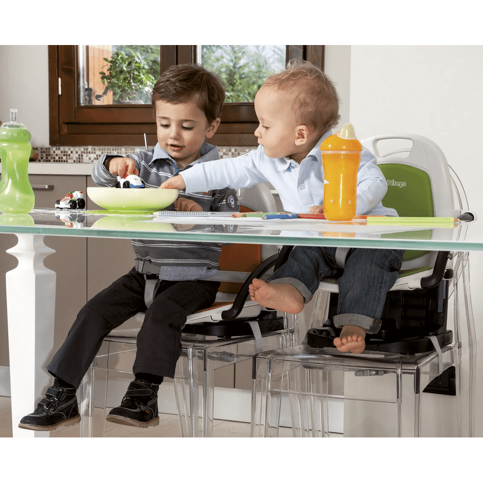 Peg Perego Rialto High Chair with two toddlers at a glass table, green backrest, orange sippy cup.