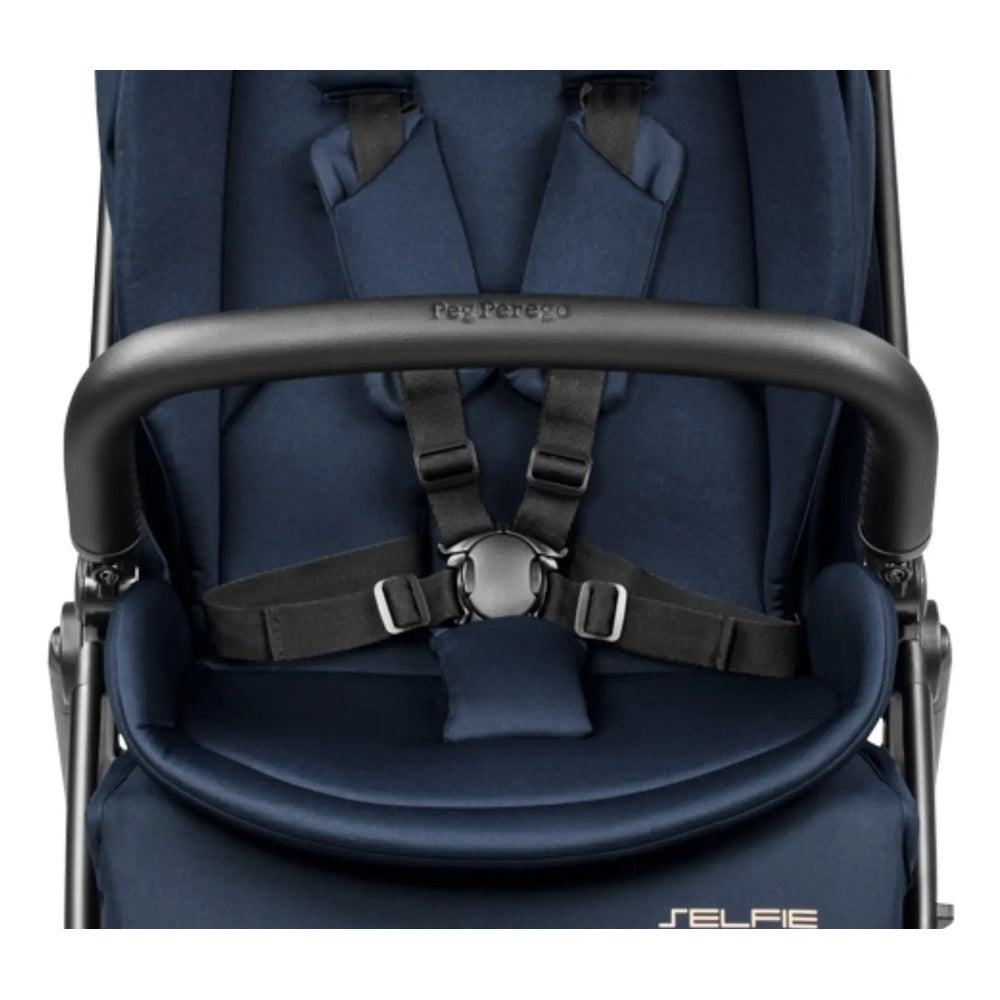 Peg Perego Selfie Plus Stroller in navy with secured 5-point harness buckled across the seat.