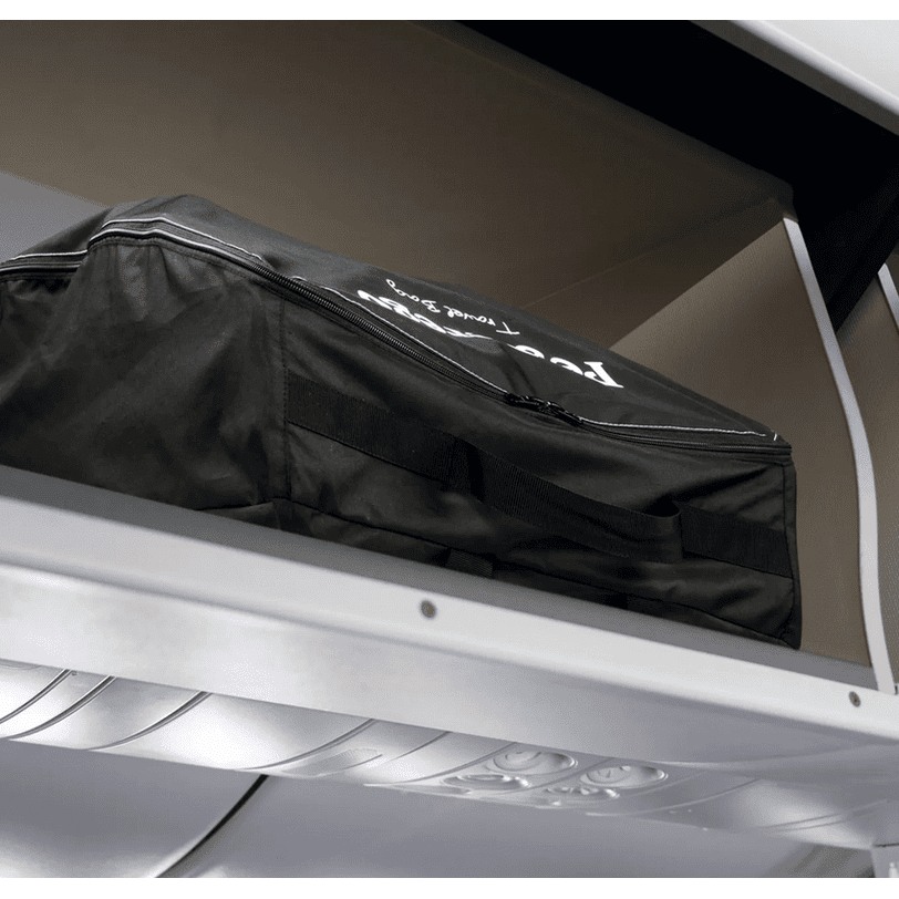 Peg Perego VOLO Travel Stroller bag in black with zipper and handles, stored on an aircraft overhead bin.