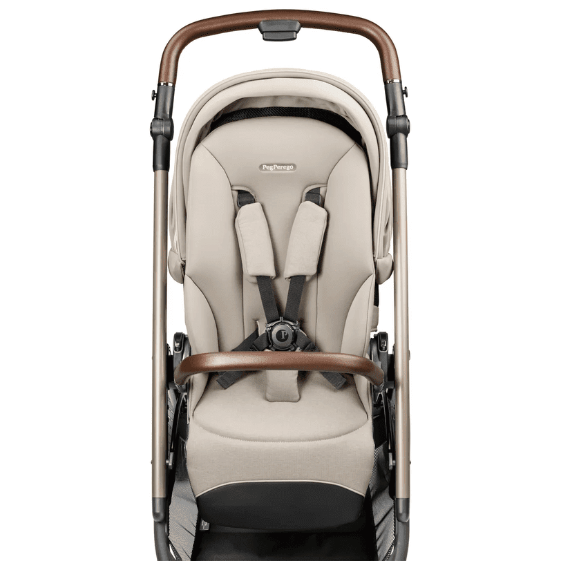 Peg Perego Velcoe TC Stroller in beige with brown handle, showing the padded 5-point harness secured.