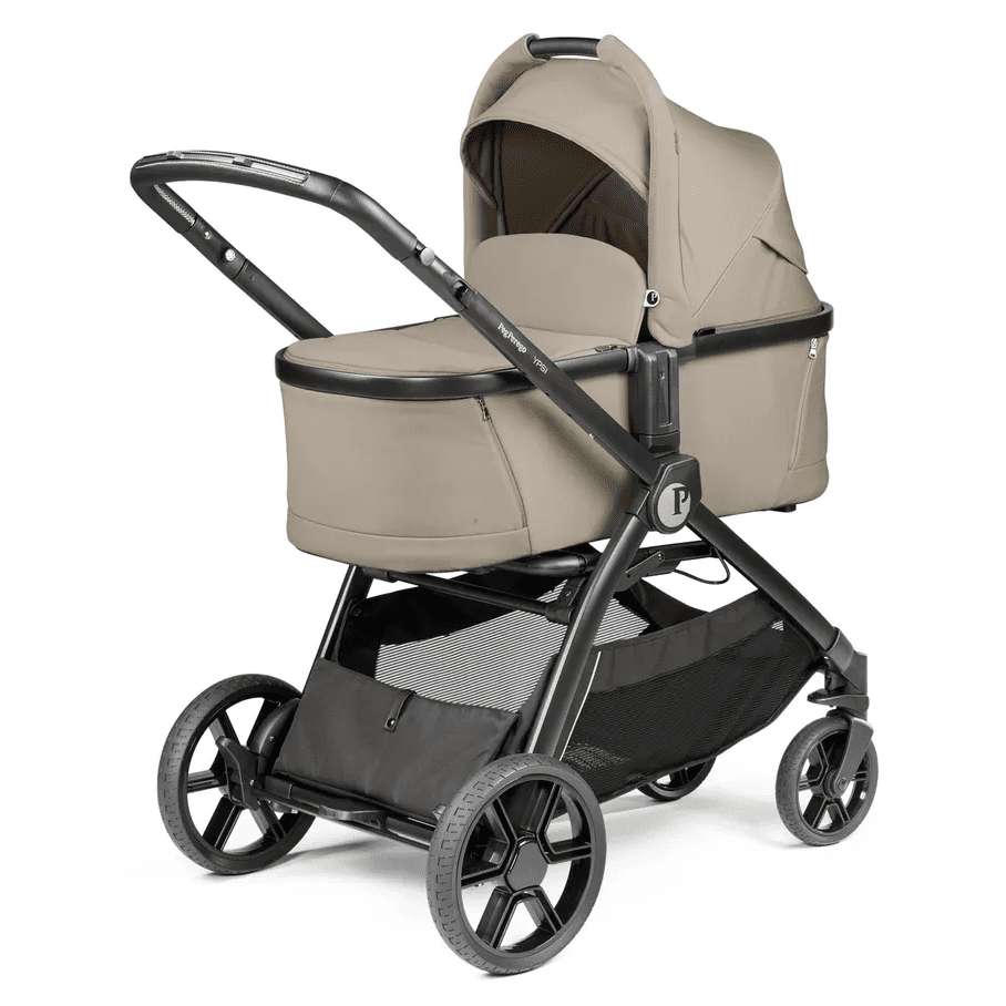 Peg Perego YPSI Bassinet with Stand By Me in beige, mounted on a black stroller frame with storage basket.