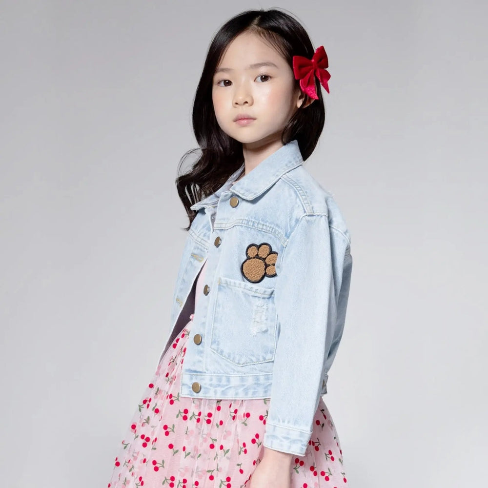 Petite Hailey Bear Patched Denim Jacket worn by a girl, calm studio pose; light blue denim with brown bear patch on the chest.