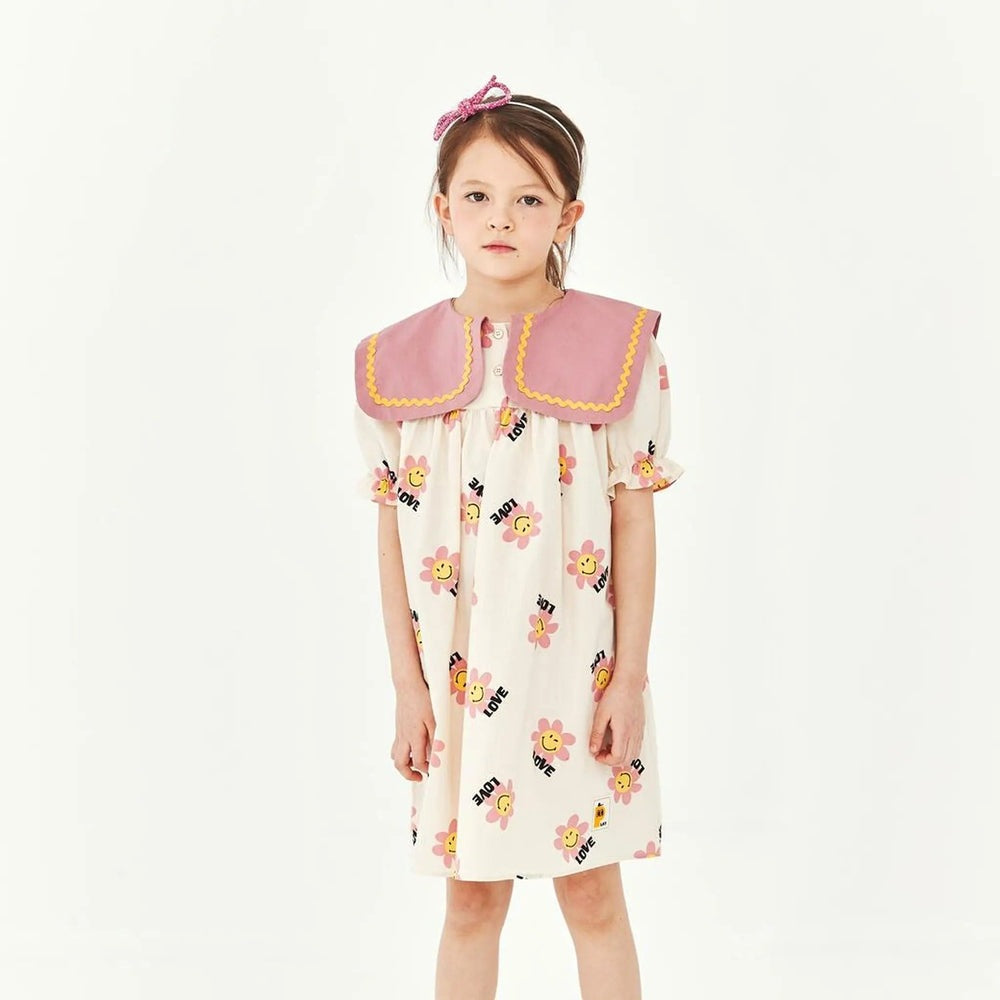 Petite Hailey Big Collar Dress Daisy Ivory; a girl stands in ivory dress with a pink oversized collar and daisy print.
