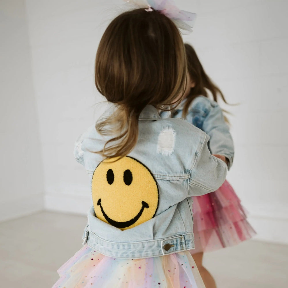 Petite Hailey Patched Denim Jacket Yellow Smile worn by a toddler with pastel tutu, back patch visible.