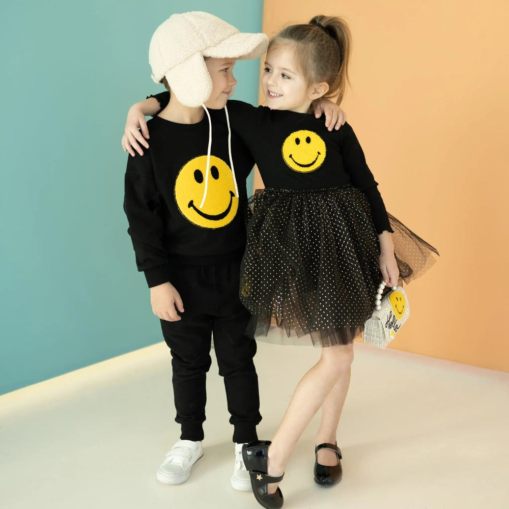 Petite Hailey Smile Smile Sweatshirts Black: two kids in matching black sweatshirts with yellow smiley, hugging and smiling.