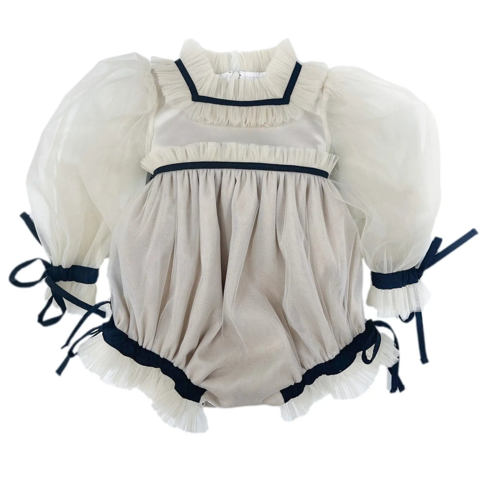 Petite Maison Kids Coco Caramel romper; ivory fabric with navy trim, puff sleeves, and tied ribbon cuffs.