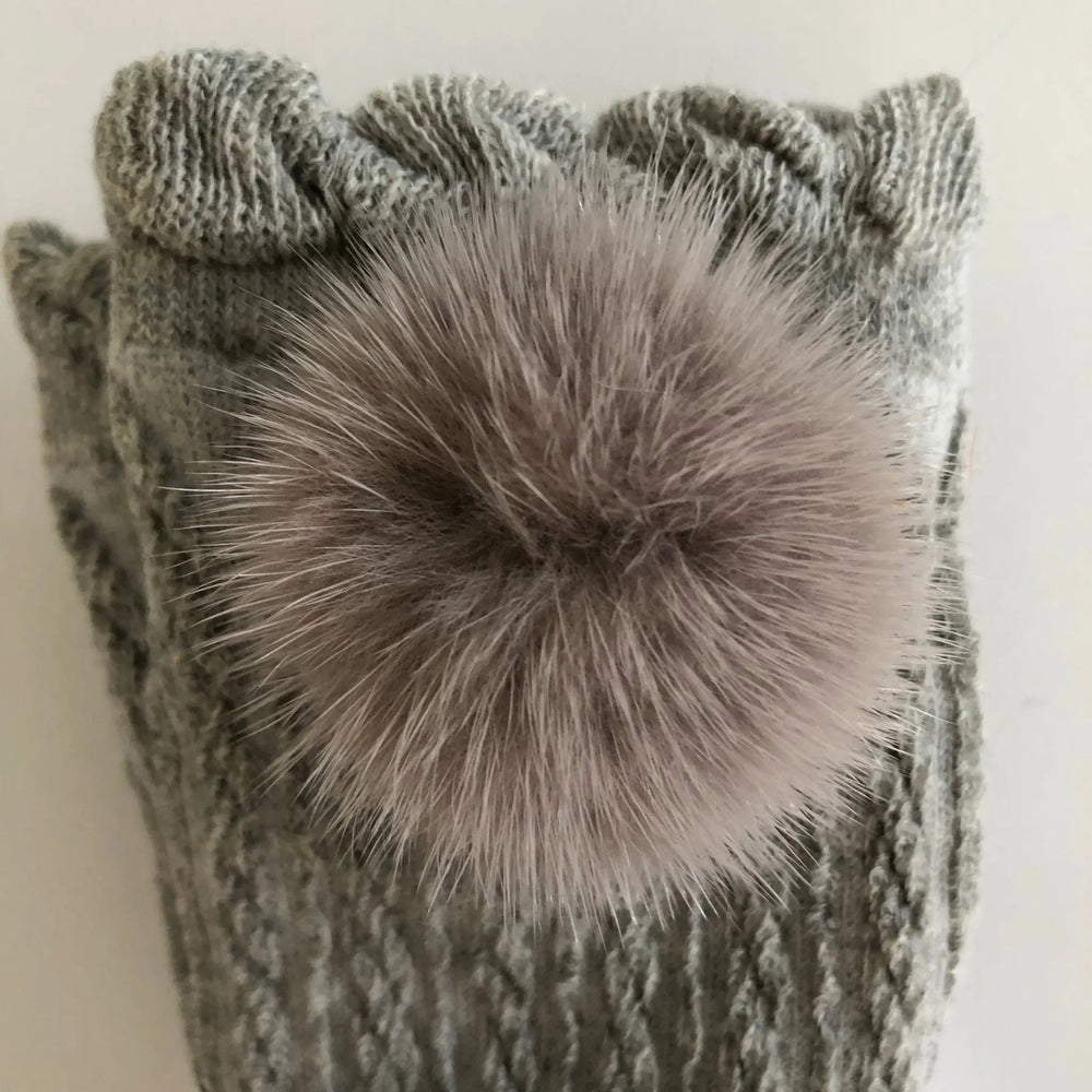 Petite Maison Kids grey knee-high socks with fluffy pom pom; ribbed knit fabric shown with the pom perched on top.