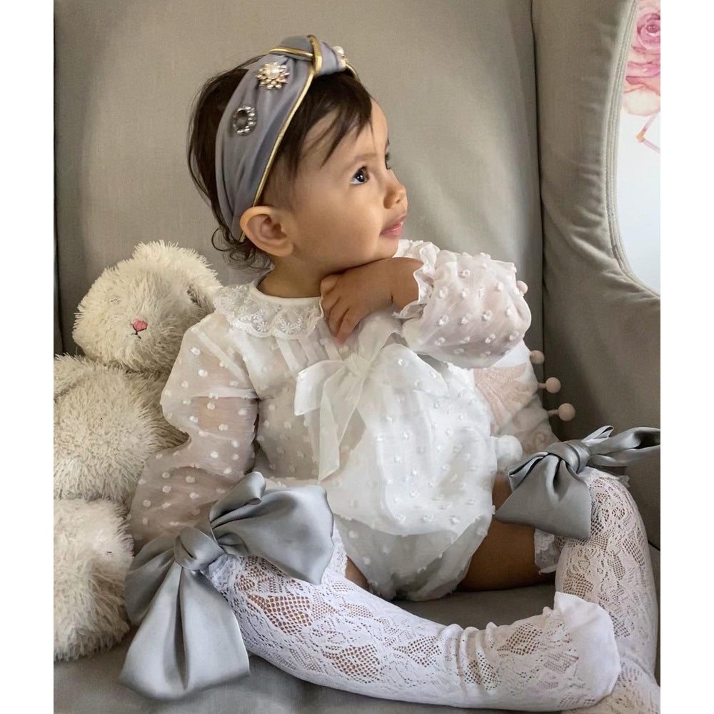 Petite Maison Kids Kylie headband in gray satin with pearl accents and gold trim worn by a baby girl.