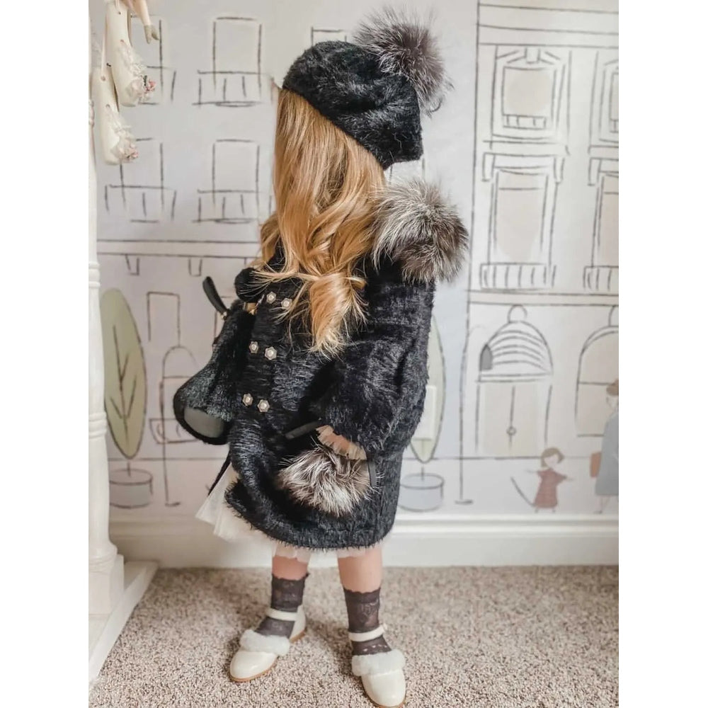 Petite Maison Kids Milana Noir Beret in black with fur pom, worn by a child in a black faux fur coat.